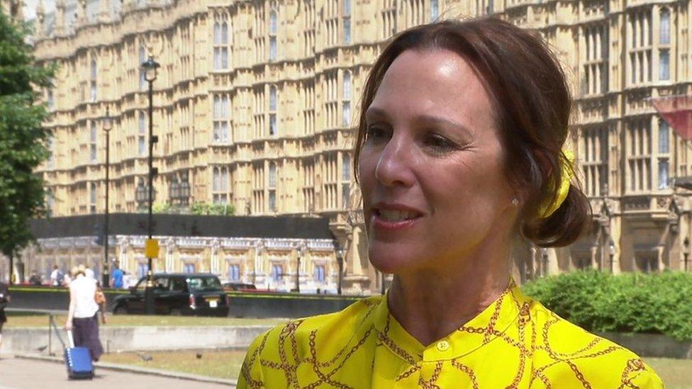 Lorin LeFave, a woman wearing a yellow satin dress and with brown hair tried back in a bun, outside Parliament.