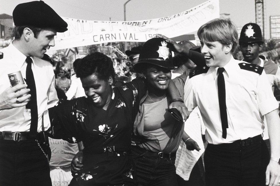 Two uniformed policemen dancing with two carnival goers at the Notting Hill Carnival, 1980s