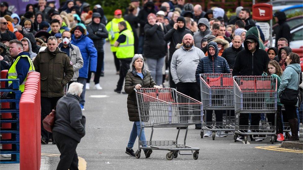 Members of the public queue to get into the Costco store in Glasgow, Scotland before opening on the morning of March 21, 2020, a day after the British government said it would help cover the wages of people hit by the coronavirus outbreak as it tightened restrictions to curb the spread of the disease.