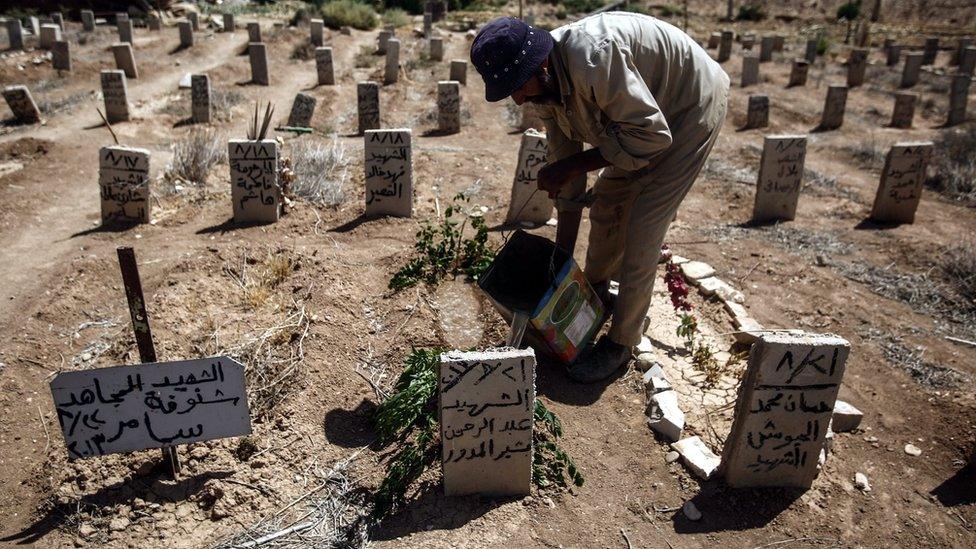 A picture made available on 22 August 2016 showing Abo Ezzo, a worker in the cemetery of Douma, drops some water and put a green branch on the tombs of Abd al-Rahman al-Moudawer, a volunteer who died while helping people in Zamalka during the chemical attack,