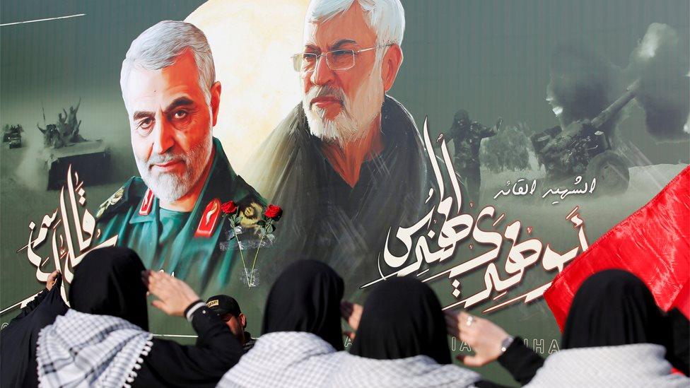 Iraqi women salute a poster showing the late Iranian General Qasem Soleimani and militia leader Abu Mahdi al-Muhandis, who were killed in a US drone strike in Baghdad in January (13 February 2020)