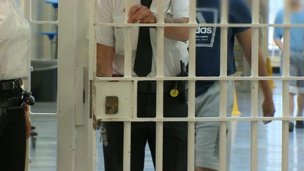 A prison officer locks a door