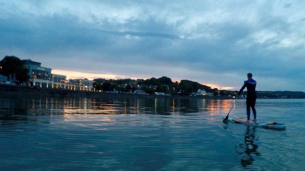 A paddle boarder heading towards Mumbles, Swansea.