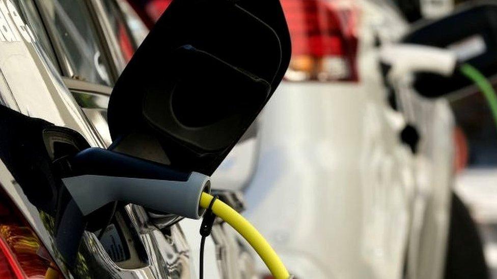 An electric car and a plug-in hybrid car charge at a public charging station