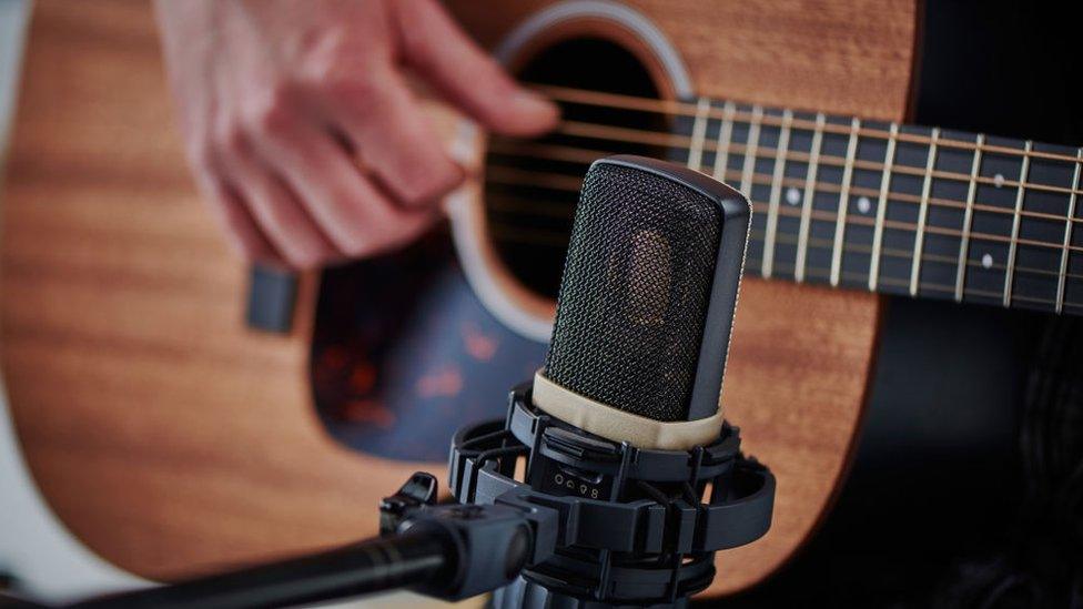 A man playing guitar in a recording session