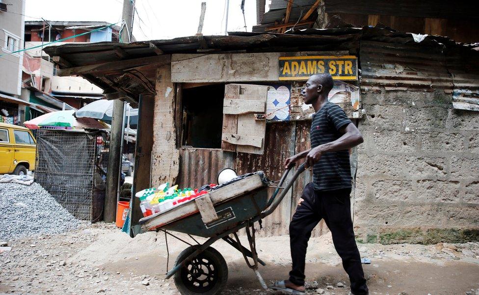 A man pushes a wheelbarrow through a street at Okepopo district in Lagos