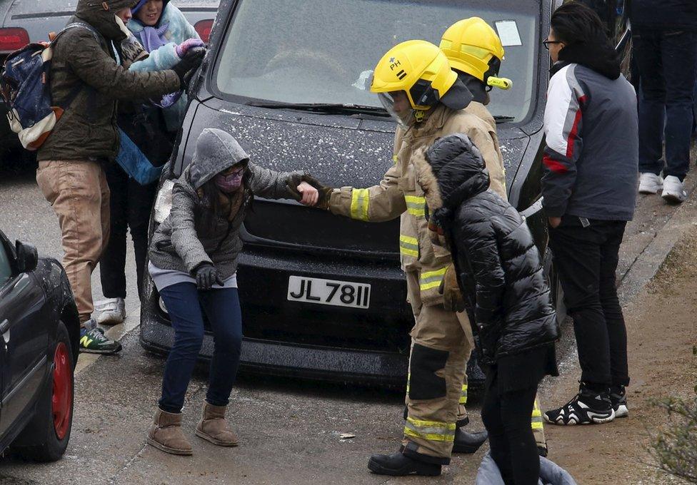 A fire fighter helps a hiker on an acy gound under sub-zero temperatures at Tai Mo Shan, the highest mountain in Hong Kong, China 24 January 2016.