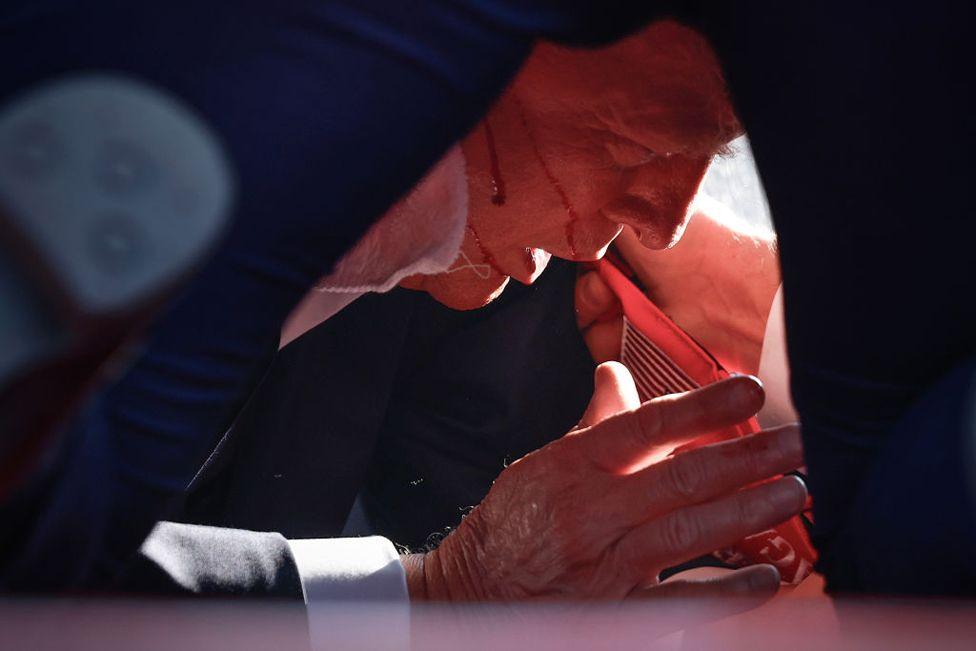 Republican presidential candidate former President Donald Trump is shown covered by U.S. Secret Service agents after an incident during a rally in Butler, Pennsylvania