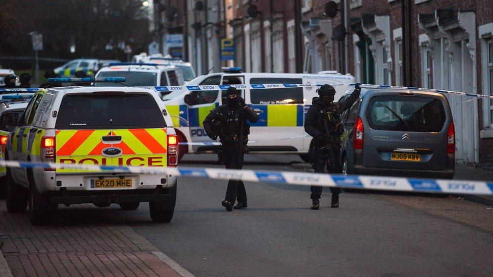 Armed police among police cars on the street