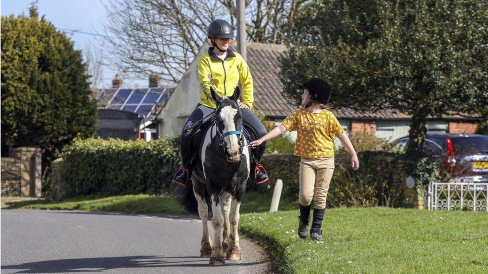 Rescue pony Micky helps owner Abi Eliot-Williams and her daughter Polly, deliver library books to members of the Hullavington Book Group in the village of Hullavington near Malmesbury, Wiltshire.