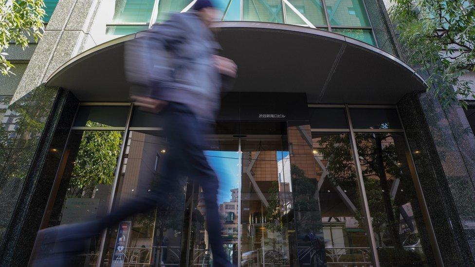 A pedestrian runs past the building where Japan's Coincheck Inc company is located in Tokyo, Japan, 27 January 2018