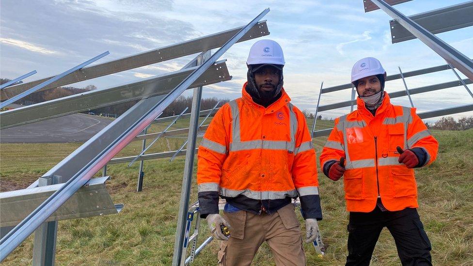 Two men in orange hi-viz standing in a PV panel mounting frame