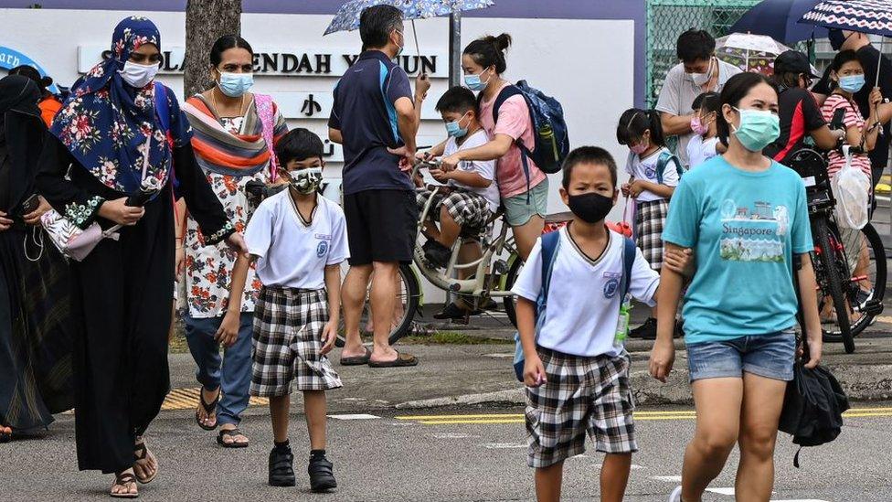 Children walk home with their guardians after school in Singapore on May 17, 2021