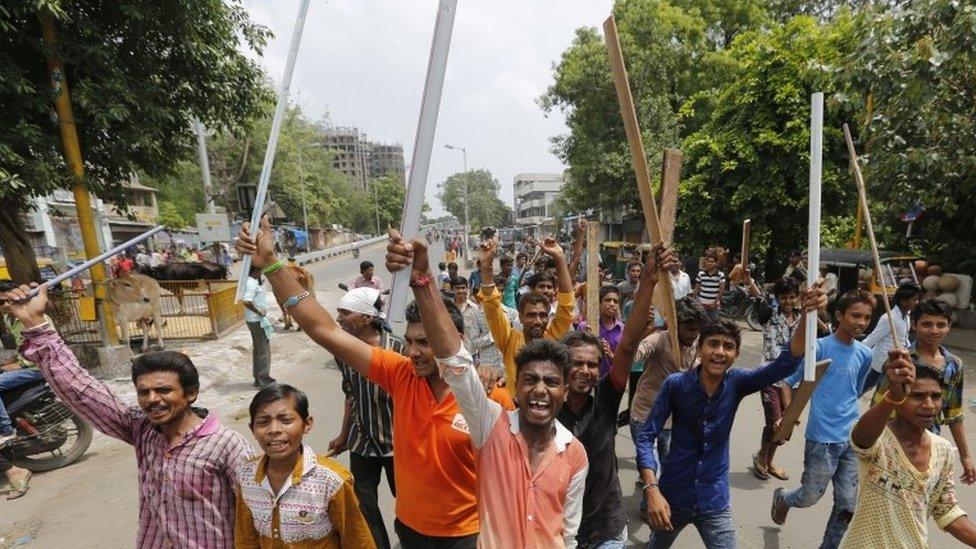 Members of India's low-caste Dalit community sticks and shout slogans in Ahmedabad, India, Wednesday, July 20, 2016.