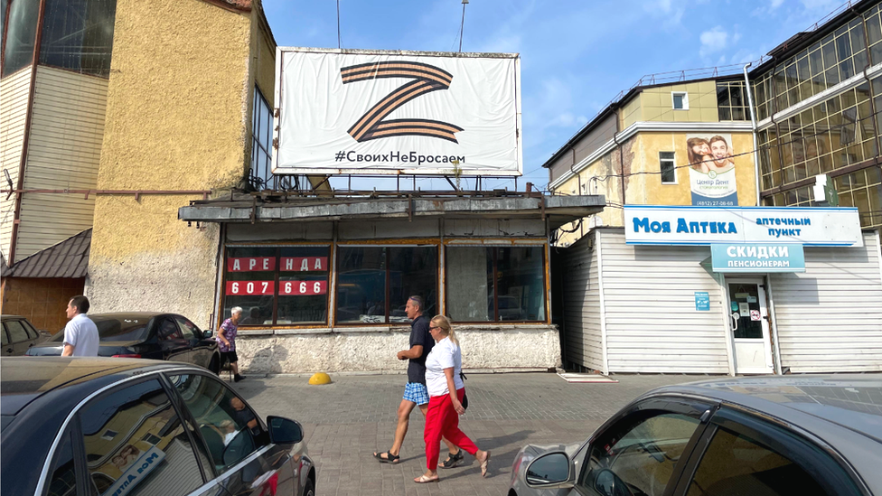 People in the western Russian city of Smolensk walk past a sign that reads: "We don't abandon our own"