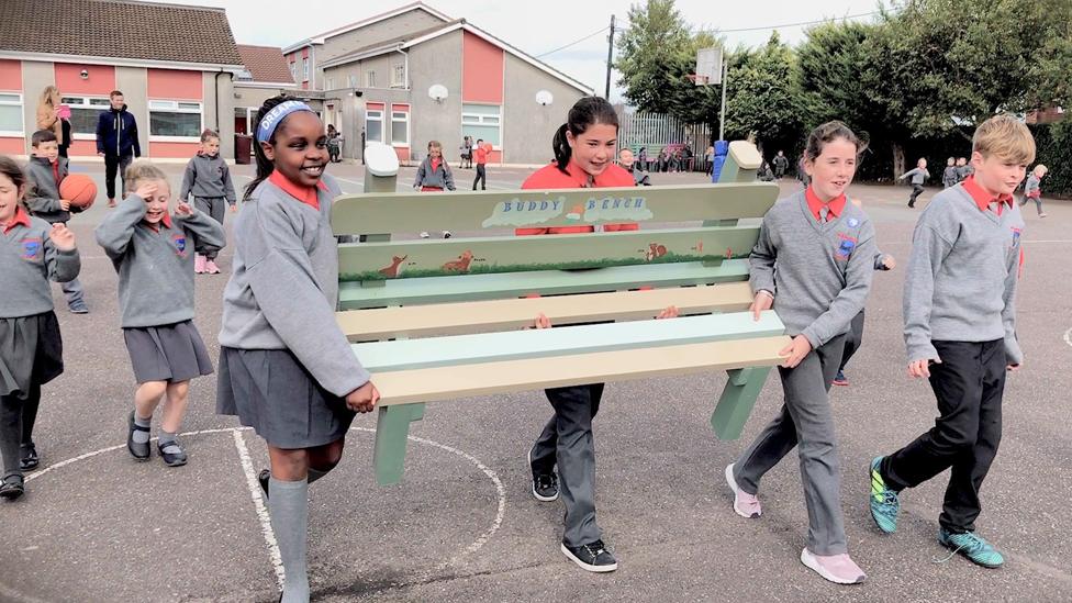 Children carrying a Buddy Bench