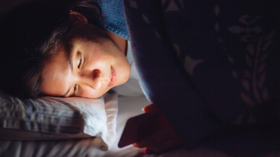 Teenage girl using her phone in bed