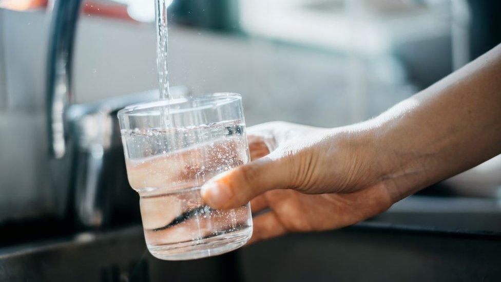 Woman filling water g;lass from tap