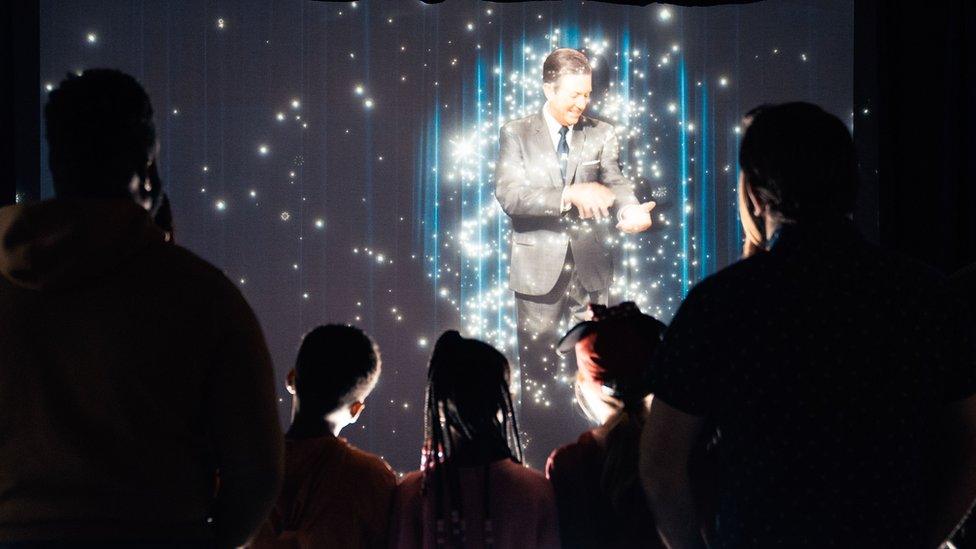 Hologram of Walt Disney in front of family of five