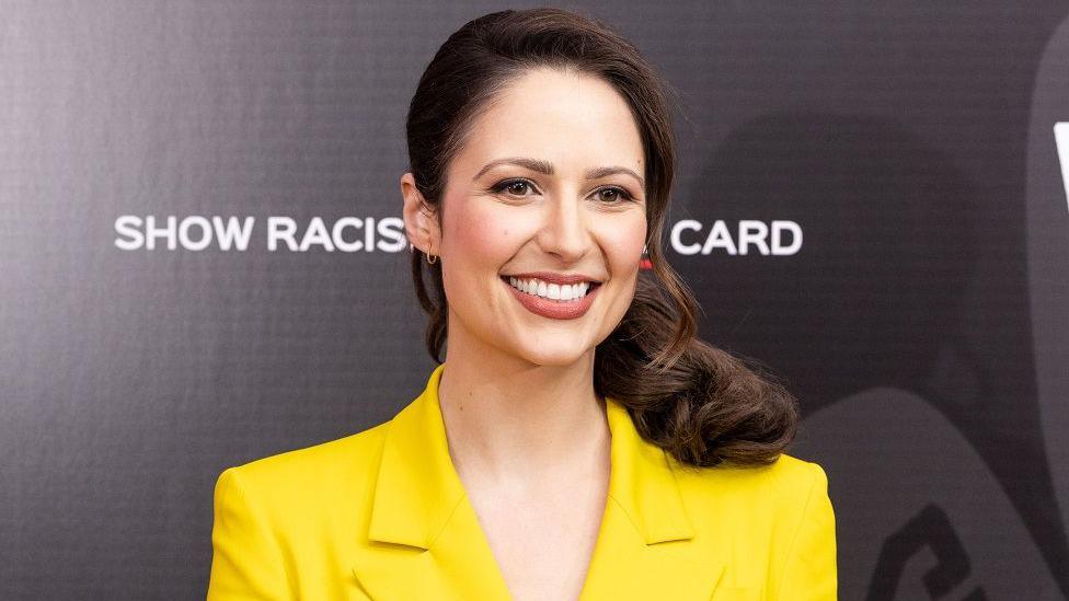  Nicola Thorp, wearing a yellow blazer, poses on the red carpet