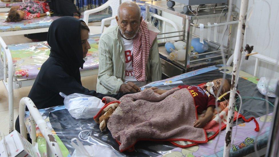 Nawal al-Maghafi sits with Shuaib's grandfather at the boy's bedside