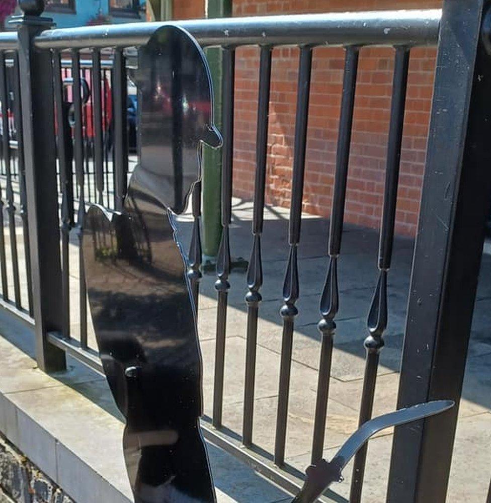 A photograph showing the metallic World War One figure having been ripped off the fence