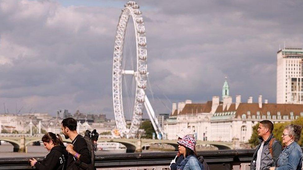 Four people in the foreground, with the London Eye over the river behind.