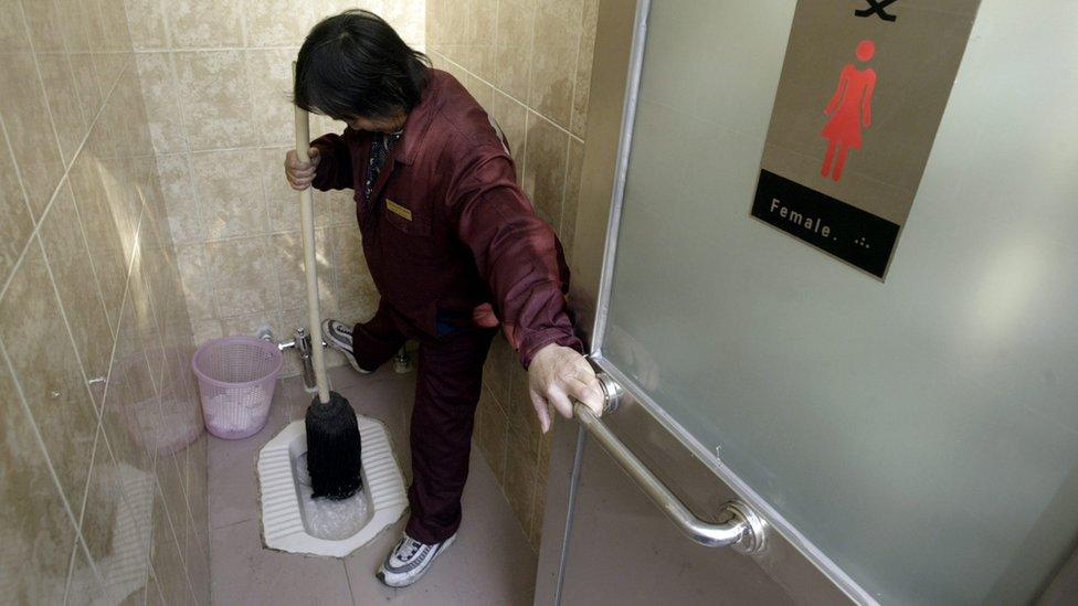 A file photo of a worker cleaning a squat toilet in China