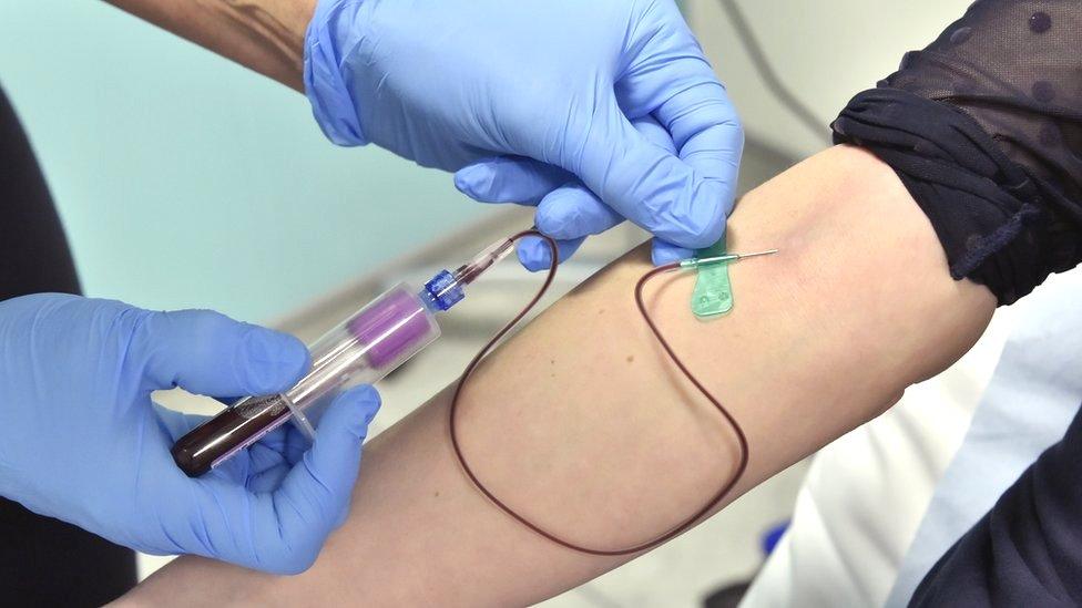 A doctor draws blood from a patient