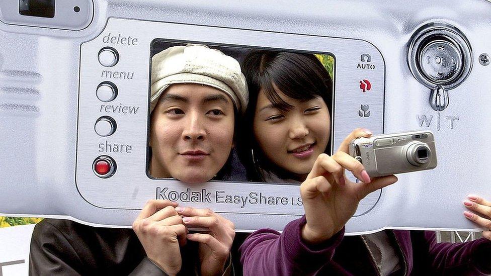 People posing with giant cardboard Kodak camera