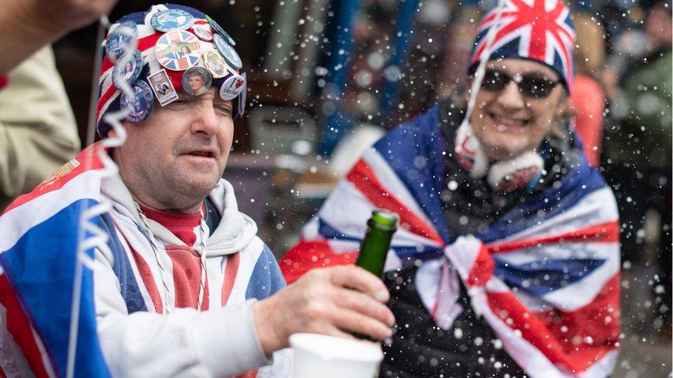 Royal fans wearing union jacks celebrate the announcement outside Windsor Castle