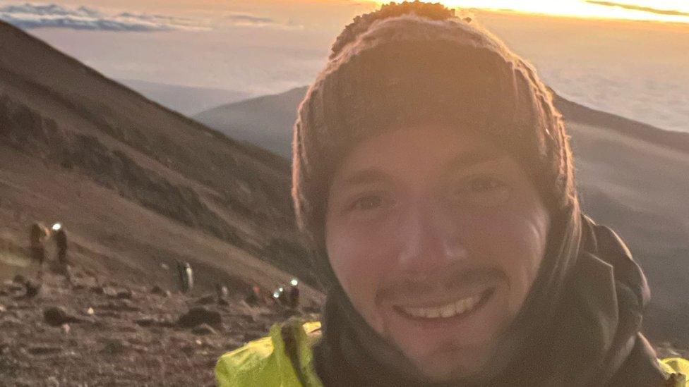 The face of a man wearing woolly hat standing on a mountain