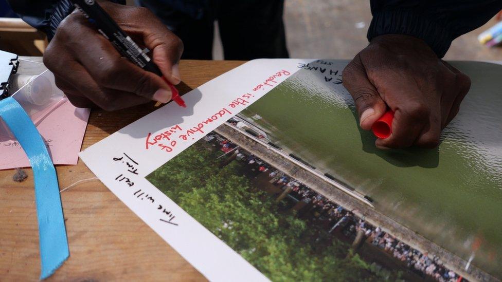 A person signs the picture of the Colston statue being pushed into the harbour