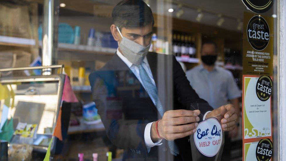 The Chancellor Rishi Sunak applies an "eat out to help out" sticker in a window