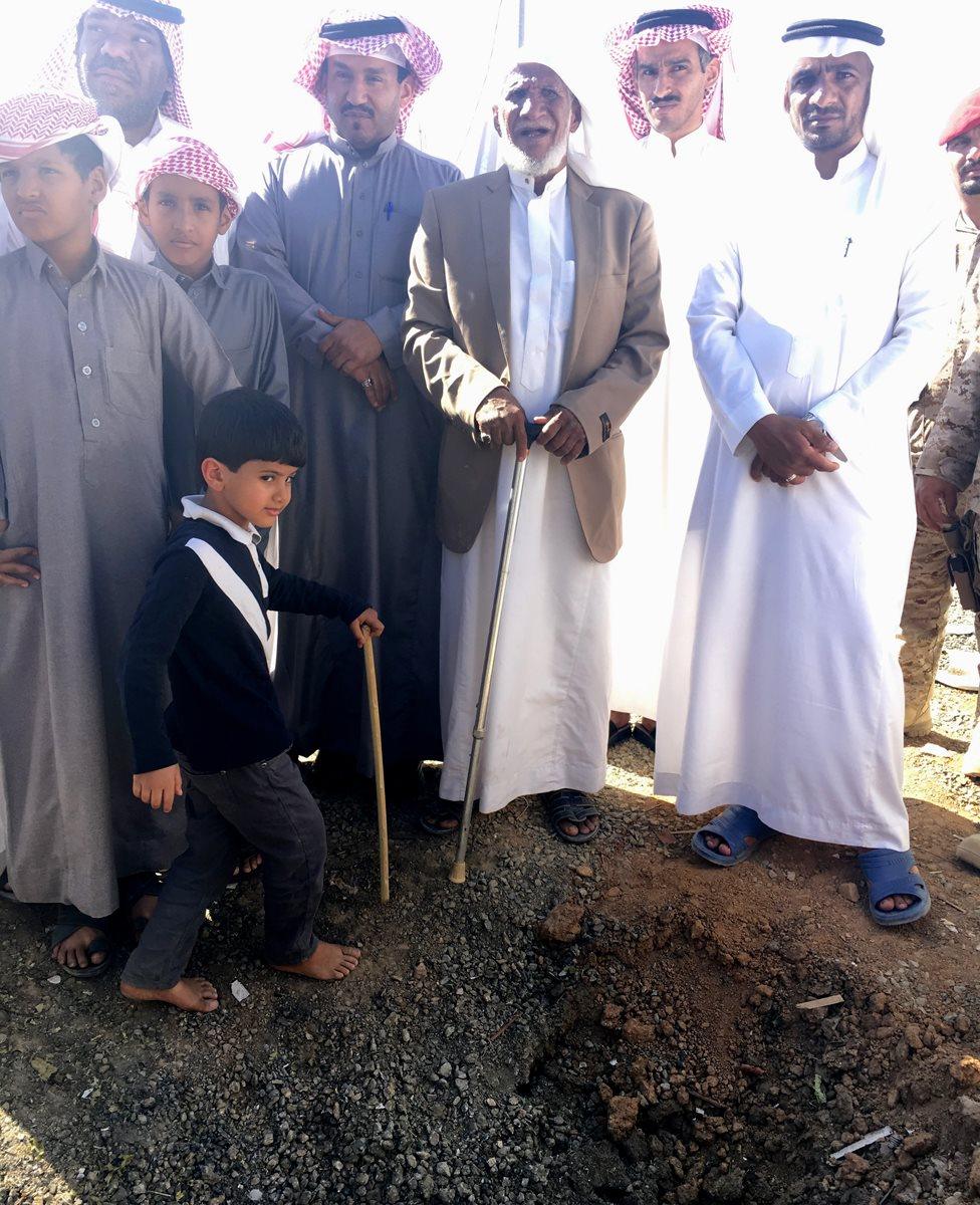 Saudi villagers beside a crater from a Yemeni rocket