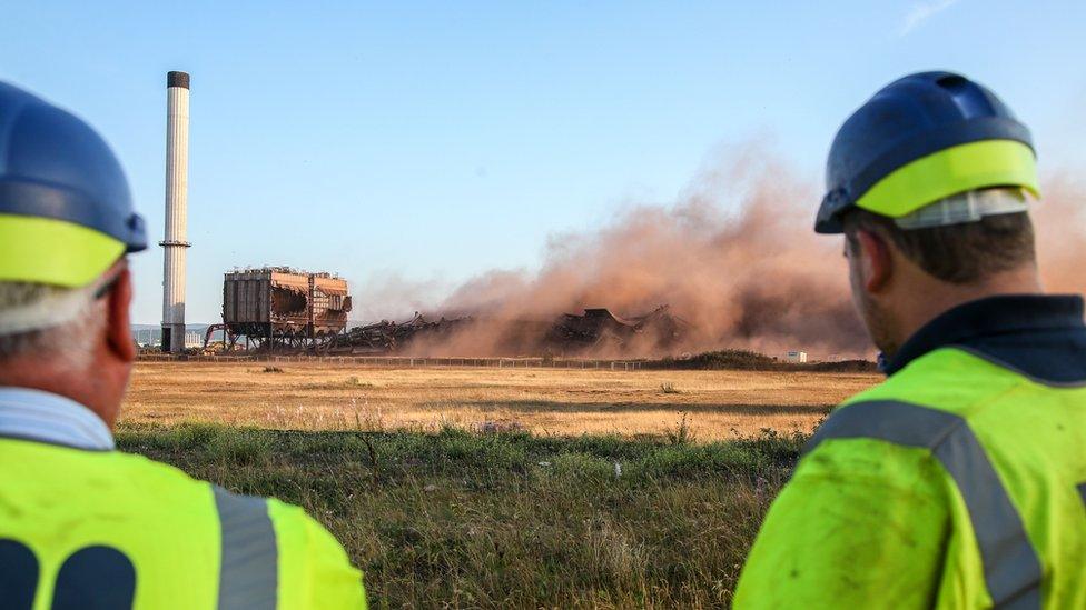 Two men look at remains of building