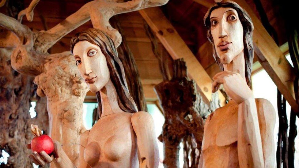 Adam and Eve sculptures have been carved out of wood.