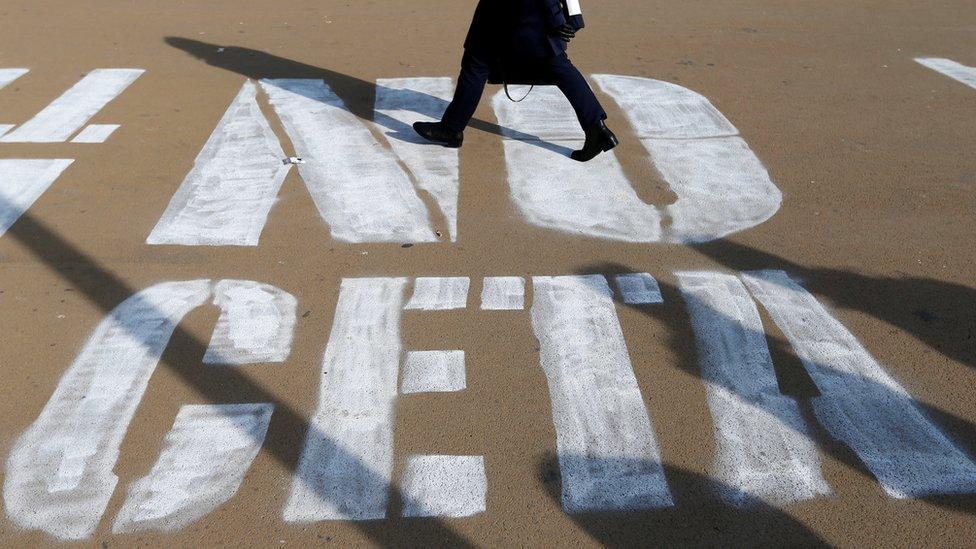 A woman walks on a graffiti reading "NO CETA", referring to the Comprehensive Economic and Trade Agreement, in Brussels