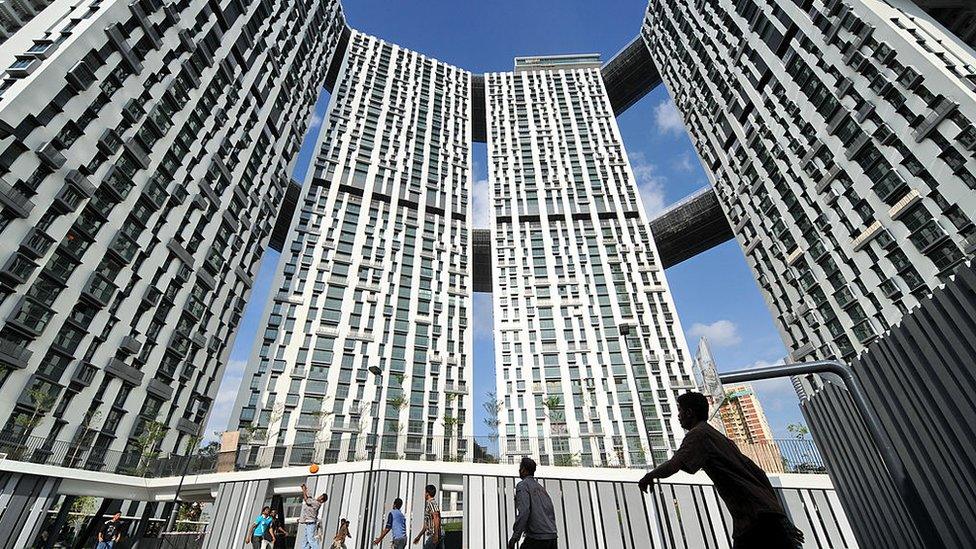 People play basketball in front of the Pinnacle@Duxton public housing apartment in Singapore.