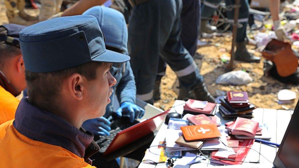 Russian rescuer checking passports collected from the wreckage of crashed plane in photo released by Russia's Emergency Ministry (2 November 2015)