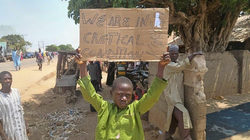 A boy holds a sign to protest against the kidnapping of nearly 300 schoolchildren this week