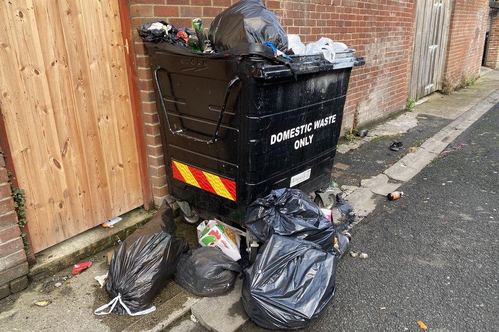 Rubbish in bags next to bin