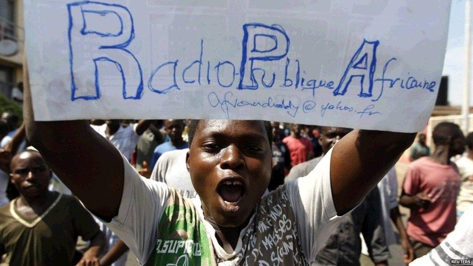 A protester carries a placard urging the government to re-open their local Radio Publique Africaine (RPA) in Burundi's capital Bujumbura