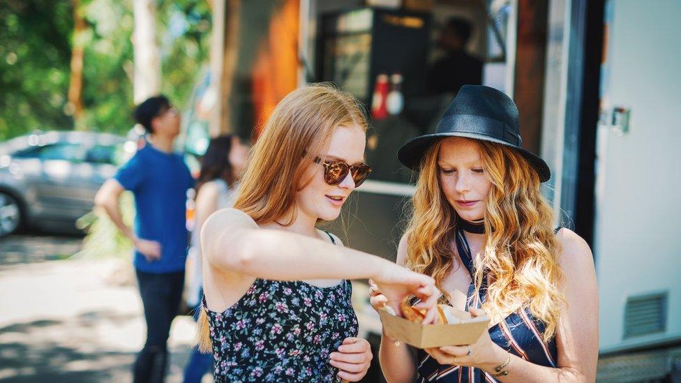 Festival goers eating food from a food truck