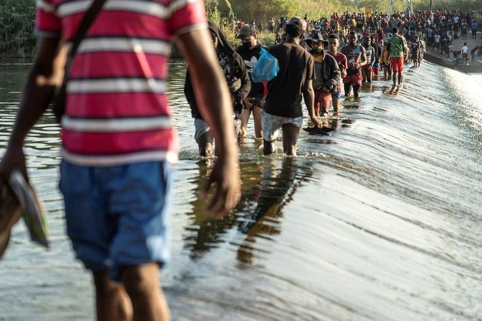 Migrants seeking asylum in the US walk in the Rio Grande river near the International Bridge between Mexico and the US, as they wait to be processed, in Ciudad Acuna, Mexico, on 16 September 2021