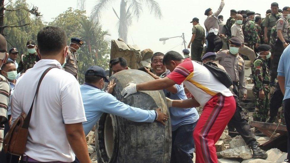 Military personnel remove an aircraft wheel at the site where an air force cargo plane crashed in Medan, Indonesia (30 June 2015)