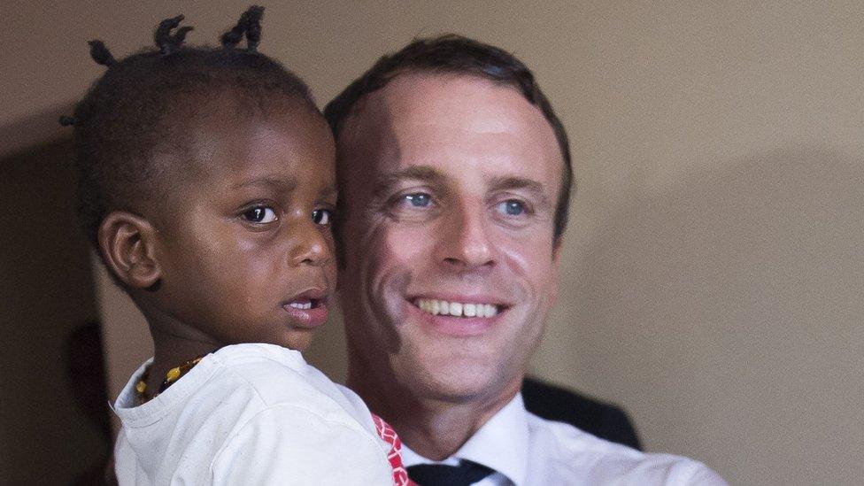 French President Emmanuel Macron holds a child as he meets residents of Quartier Orleans, 29 September 2018