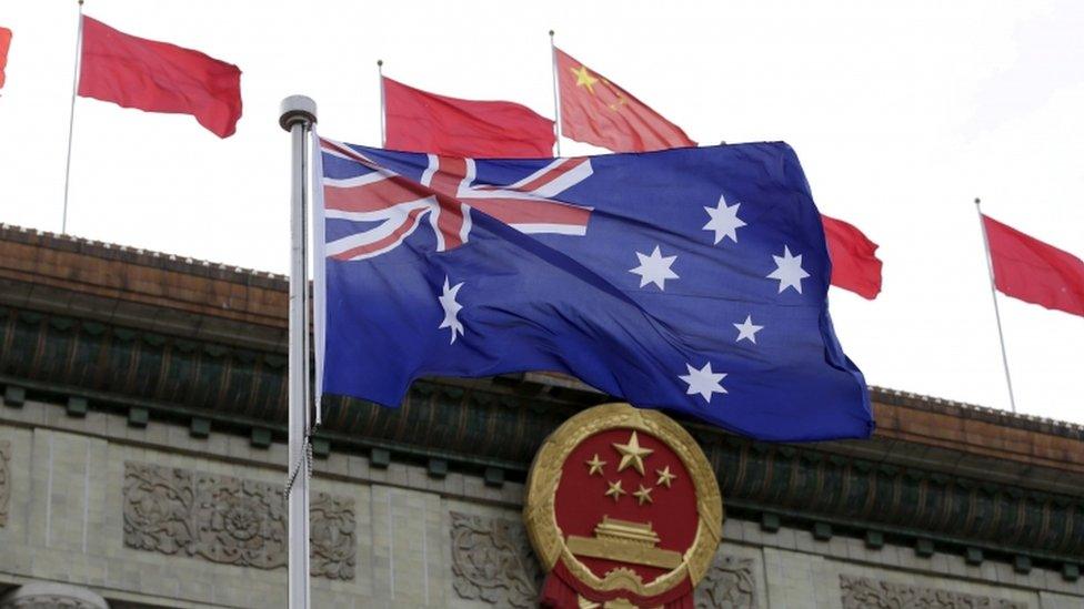 An Australian flag in front of Chinese flags