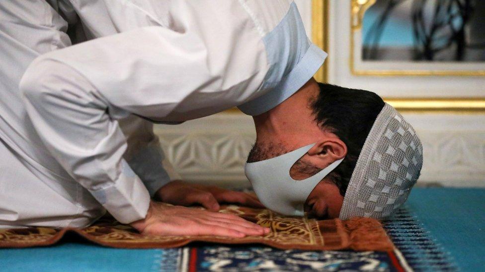 A man prays whilst wearing a face mask