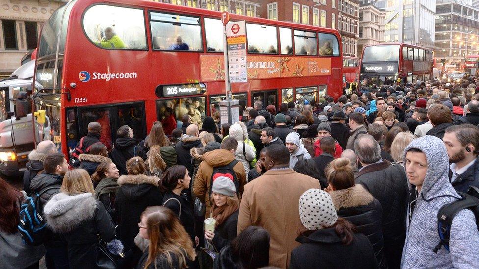 Crowds of people queuing for buses at Bishopsgate in the City of London